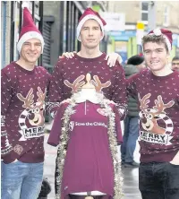  ??  ?? XMAS SPIRIT Hearts’ Ross Callachan, left, John McLaughlin, centre, and Euan Henderson help decorate Save The Children stores ahead of Christmas Jumpers Day on December 15