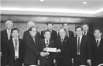  ??  ?? President of Sibu Chinese Chamber of Commerce and Industry Dr Hii Sui Cheng (second left) receiving a cheque from Hu on behalf of the Sibu Division Chinese independen­t schools witnessed by Dr Sim (third left) and others.