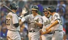  ?? Stacy Revere / Getty Images ?? Bat in hand, A’s starter Brett Anderson welcomes Dustin Garneau (3) after Garneau’s threerun homer in the second.