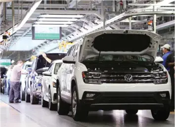  ?? STAFF FILE PHOTO ?? Employees work around vehicles moving down the assembly line at the Volkswagen Assembly Plant.