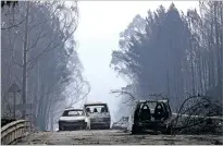  ?? ARMANDO FRANCA THE ASSOCIATED PRESS ?? Burnt cars block the road Sunday between Castanheir­a de Pera and Figueiro dos Vinhos, central Portugal. Raging forest fires in central Portugal killed more than 60 people, many of them trapped in their cars as flames swept over a road.
