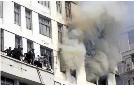  ?? — ABHIJIT MUKHERJEE ?? Smoke billows out of windows after a fire broke out on the fifth floor of a highrise office building at Park Street in Kolkata on Monday. According to reports, a short circuit from the server of a private bank on the fifth floor may have caused the fire. No casualties were reported.
