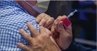  ?? Boston Herald file ?? KEEPING TRACK: A man gets a COVID-19 booster shot at the Museum of Science on Nov. 14 in Boston.