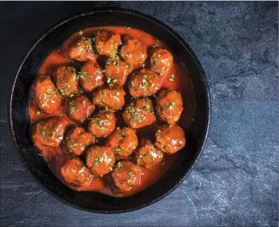  ?? TRIBUNE CONTENT AGENCY ?? These hearty meatballs are simmered in tomato sauce before serving.