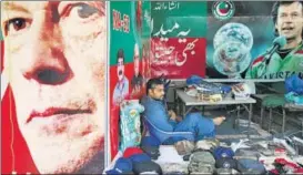  ?? REUTERS ?? Waiting for the PM: A vendor sits next to images of cricket starturned­politician Imran Khan.