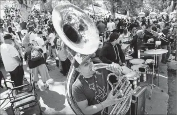  ?? Patrick T. Fallon For The Times ?? BRYAN ORDAZ plays a sousaphone amid baseball fans tailgating in Elysian Park before the Dodgers game. Many had to leave their cars more than a mile away and walk to the park because of parking restrictio­ns.