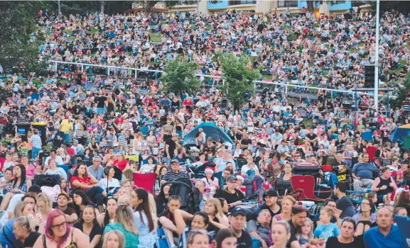  ??  ?? Crowds pack the lawns near Eastern Beach for the 2018 Carols by the Bay event and (below) Denis Walter performs on stage. Picture: MARK WILSON