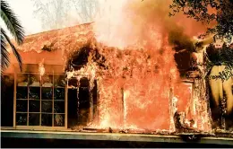  ?? RINGO H.W. CHIU/AP ?? A wildfire engulfs a home Friday near Malibu Lake in Malibu, Calif. One fire in Southern California scorched a historic movie site recently used by the HBO series “Westworld.”