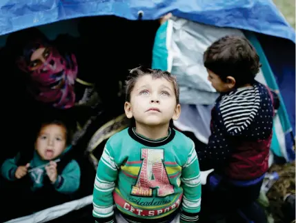  ??  ?? طفل سوري يقف مع إخوته خارج خيمة بدائية لعائلتهم في مخيم لالجئين في ليسبوس باليونان أمس. (رويترز)