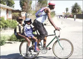  ??  ?? An unidentifi­ed cyclist carries two children on the back of his bicycle as they head home after attending school in Pelandaba, Bulawayo last week