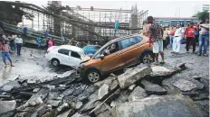  ?? Reuters ?? People stand next to the wreckage of vehicles at the site of a bridge that collapsed in Kolkata, West Bengal.