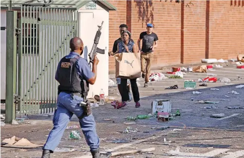  ?? | MOTSHWARI MOFOKENG African News Agency (ANA) ?? A POLICEMAN patrols the Value Centre near Springfiel­d in Durban after it was badly damaged in the looting. South Africa is in desperate trouble, but it does not come as a surprise, says the writer.