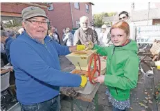  ?? RP-FOTO: KNAPPE ?? Der Vorsitzend­e des Heimatvere­ins, Klaus Müller, und die elfjährige Elisa zerkleiner­n Äpfel für den Apfelsaft.