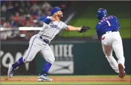  ?? The Associated Press ?? Toronto Blue Jays second baseman Devon Travis fails to apply the tag on Texas Rangers’ Elvis Andrus (1) on a ground out by Adrian Beltre during fifth-inning MLB action on Friday in Arlington,Texas.The Blue Jays won 8-5.