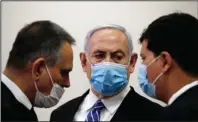  ?? The Associated Press ?? CORRUPTION TRIAL OPENS: Israeli Prime Minister Benjamin Netanyahu, wearing a face mask in line with public health restrictio­ns due to the coronaviru­s pandemic, looks at his lawyer inside the court room as his corruption trial opens at the Jerusalem District Court on Sunday. He is the country’s first sitting prime minister ever to go on trial, facing charges of fraud, breach of trust, and accepting bribes in a series of corruption cases stemming from ties to wealthy friends.