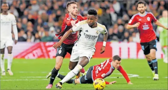  ?? ?? Vinicius es agarrado en carrera por Mingueza durante el partido de ayer en el Bernabéu.