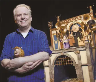  ?? AP PHOTO ?? KING OF THE CASTLE: Nick Park, director of ‘Early Man’ and the voice of Hognob, top right, cradles the puppet as he poses in front of a film set.