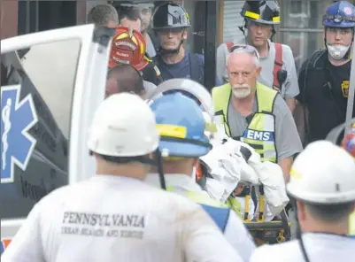  ??  ?? Rescue workers transport Megan Angelone to an ambulance after she was rescued from a collapsed building on Wednesday in Washington, Pa. For more about the building collapse, see Page A-12.