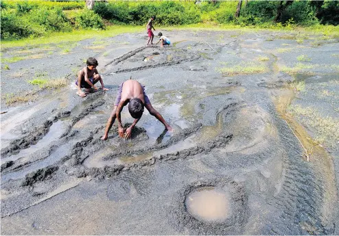  ?? SAURABH DAS / THE ASSOCIATED PRESS ?? Children play on farmland destroyed by asbestos sediments in Roro, India, in 2014. More than 50 countries have banned all forms of asbestos, but the industry has found new markets in developing countries, particular­ly in Asia.