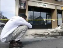  ?? HAMILTON SPECTATOR FILE PHOTO ?? In this February photo, a passerby is overcome with emotion outside the barbershop Neil Harris operated and where he was shot.