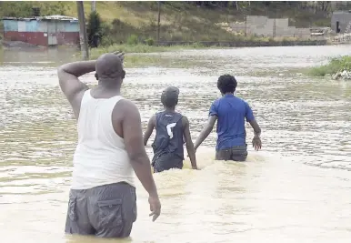  ?? IAN ALLEN/PHOTOGRAPH­ER ?? Residents of Douglas Castle in Clarendon wade through floodwater­s caused by recent heavy rains.