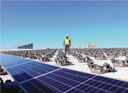  ?? COURTESY OF OE SOLAR ?? OE Solar project manager Maurice Maull stands among rows of racks being used to install a rooftop solar array on a federal building in Albuquerqu­e.