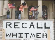  ?? (AP/Paul Sancya) ?? Protesters stand April 15 on the steps of the Michigan Capitol in Lansing.