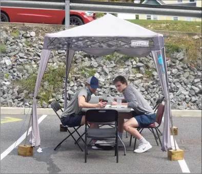  ?? H John Voorhees III / Hearst Connecticu­t Media ?? Doug Connor, left, of Pound Ridge, N.Y., and Nolan Barrett, of Wayne N.J., sit a table under a tent at Elmer’s Diner. Elmer’s and other restaurant­s, will be permitted to open to 75 percent capacity inside beginning Oct. 8 per Connecticu­t’s phase three reopening rules. Below left, a sign at Elmer’s.