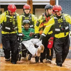  ?? ANDREW DYE / WINSTON-SALEM JOURNAL ?? Winston-Salem (N.C.) Fire Department firefighte­rs move James Benjamin from his home a as flood waters rise on Thursday.