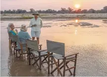  ?? Tribune News Service ?? Bilimungwe manager Alex Steward has a surprise for her guests: the evening sundowner in the Luangwa River, barefoot, with the Chinden Hills in the background.