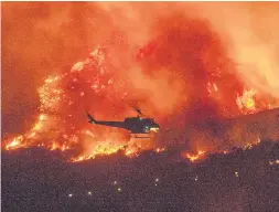  ?? RINGO H.W. CHIU THE ASSOCIATED PRESS ?? A helicopter prepares to drop water on a wildfire in Yucaipa, Calif., on Saturday. The explosive blaze was just five per cent contained on Sunday.