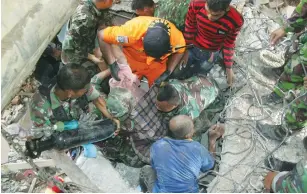  ?? (Reuters) ?? RESCUE WORKERS carry a survivor from a fallen building after an earthquake in Trienggade­n, in the northern province of Aceh, yesterday.