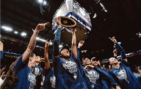  ?? Steph Chambers/Getty Images ?? UConn’s Aaliyah Edwards lifts the Portland 3 Regional Championsh­ip trophy after her team’s 80-73 win over USC in the Elite 8 at Moda Center on Monday in Portland.