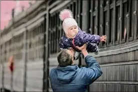  ?? Vadim Ghirda / Associated Press ?? A man plays with a child Saturday in Kyiv, Ukraine, before she boards a train bound for Lviv. Fighting raged in the outskirts of Ukraine's capital, and Russia kept up its bombardmen­t of other resisting cities.