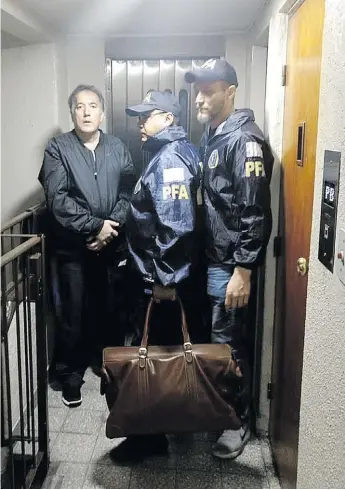  ?? PF ?? En el palier. Oscar Thomas, recién detenido en su departamen­to, es llevado a la alcaidía.