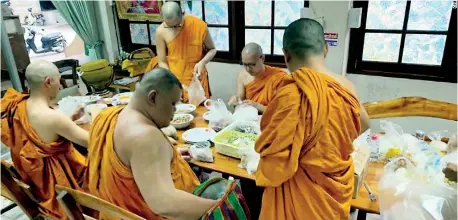  ??  ?? Monks at Yannawa temple in Bangkok prepare to partake their meals.