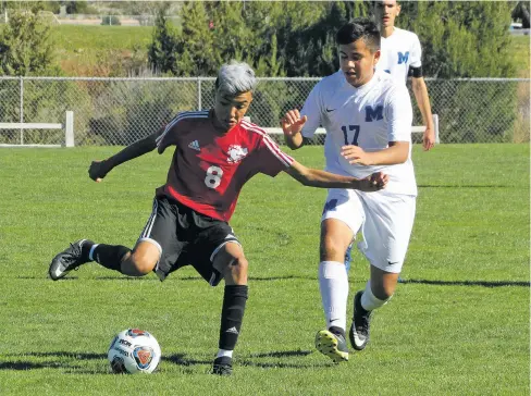  ?? PHOTOS BY JAMES BARRON/THE NEW MEXICAN ?? Monte del Sol freshman midfielder Axel Lozoya, left, shoots the ball while St. Michael’s freshman David Candelas defends during the first half of the Class 1A/3A boys quarterfin­al match Wednesday at the New Mexico Soccer Tournament Complex at Santa Ana Pueblo. Lozoya recorded a hat trick to lead the Dragons to their second semifinal berth in program history with a 3-1 win.