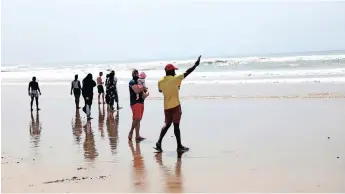  ?? | KHAYA NGWENYA African News Agency (ANA) ?? BEACHGOERS get their toes wet on one of Durban’s forbidden beaches yesterday, while a lifeguard warns people in the water to get out.