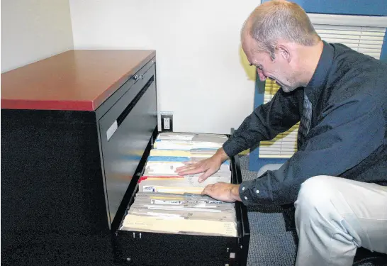  ?? FILE PHOTO ?? In this 2007 photo, RCMP Const. Gordie Matthews, of the Northern Region Major Crime Unit, looks through the files that have been generated by the investigat­ion into the murder of Amherst resident Sadie Rogers in 1981. The entire filing cabinet is filled with documents related to the case, but police are no closer to solving the crime and are asking people’s assistance in helping them solve it.