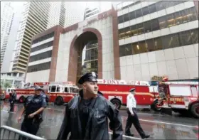  ?? RICHARD DREW — THE ASSOCIATED PRESS ?? New York City Police and Fire Department personnel secure the scene in front of a building in midtown Manhattan where a helicopter crash landed, Monday. The Fire Department says the helicopter crash-landed on the top of the tower, which isn’t far from Rockefelle­r Center and Times Square.