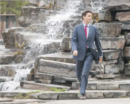  ?? LYLE ASPINALL ?? Prime Minister Justin Trudeau walks past a man-made waterfall to his morning meeting at the Delta Lodge at Kananaskis west of Calgary on Tuesday. The federal Liberal cabinet was wrapping up three days of meetings at the lodge.