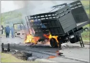  ?? THE ASSOCIATED PRESS ?? National Civil Police agents stand next to a burning army truck during clashes with peasants on Thursday.