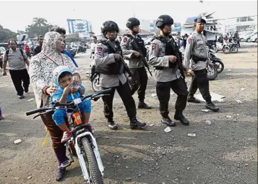  ?? — AP ?? Heightened vigilance: Policemen patrolling an area near the site of the bombings in Jakarta.