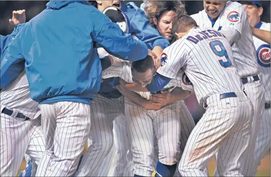  ??  ?? The Cubs’ Alfonso Soriano (center) is mobbed by his teammates after driving in the winning run with a 10th-inning single Tuesday.
| TOM CRUZE~SUN-TIMES