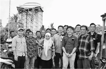  ??  ?? Norah (centre) poses with officers from various department­s and villagers after a visit to the HLT project site (in the background).