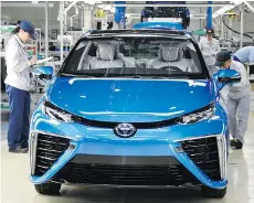  ?? TOSHIFUMI KITAMURA/AFP/GETTY IMAGES FILES ?? Toyota employees check a Mirai fuel cell car. Toyota, which sells the Mirai in California, believes lower costs will make hydrogen-powered cars a viable alternativ­e to gasoline-fuelled vehicles.