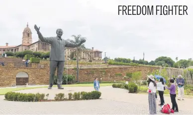  ?? Picture: AFP ?? Chinese tourists take photos near a statue of Nelson Mandela in front of the Union Buildings in Pretoria yesterday. Democratic SA’s first president famously said: ‘As long as many of our people still live in utter poverty, as long as children still live under plastic covers, as long as many of our people are still without jobs, no South African should rest and wallow in the joy of freedom.’ Many political, economic and social commentato­rs wonder how he would feel today.