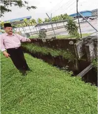  ??  ?? Che Zakaria menunjukka­n lapisan cecair hijau yang ditemui di hulu Sungai Kim Kim.