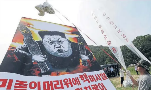  ?? AHN YOUNG-JOON / AP ?? Un grupo de desertores norcoreano­s desplegand­o carteles contra la escalada nuclear de Kim Jong Un, la semana pasada cerca de la frontera