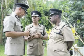  ?? (Photo: Philp lemonte) ?? Commission­er of Police Major General Antony Anderson (centre) and Assistant Commission­er of Police Ealan Powell (right) listen attentivel­y to a point being made by Deputy Commission­er of Police Clifford Blake during a tour of the Grange Hill community on May 3, 2018, a day after seven members of the community were shot dead and eight injured by marauding gunmen.